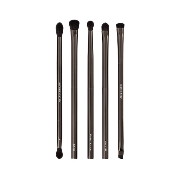 Makeup brush set with six dark bristles and sleek gray metallic handles, upright.
