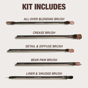 Makeup brush set laid out, multiple face and eye brushes with dark bristles.