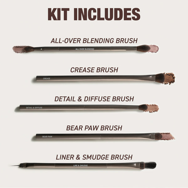 Makeup brush set laid out, multiple face and eye brushes with dark bristles.