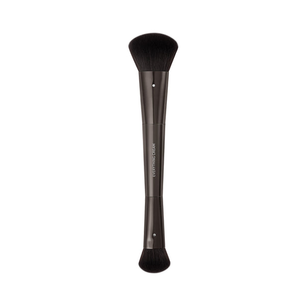 Makeup brush with short black bristles and a dark straight handle.