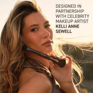 Kelli Anne makeup brush with black bristles, used on a model’s cheek.