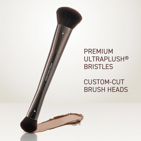 Angled makeup brush with black bristles and metallic handle beside a cream swatch.
