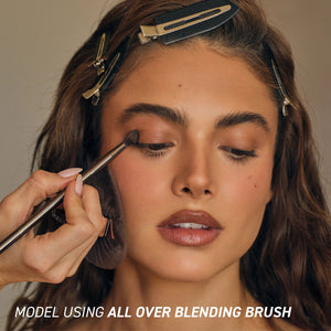 Makeup eye blending brush in use, with dark bristles and metallic handle.