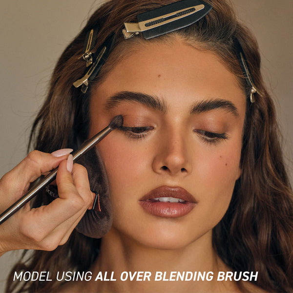 Makeup eye blending brush in use, with dark bristles and metallic handle.